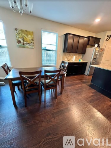 A kitchen with dark wood floors and a dining table with chairs.