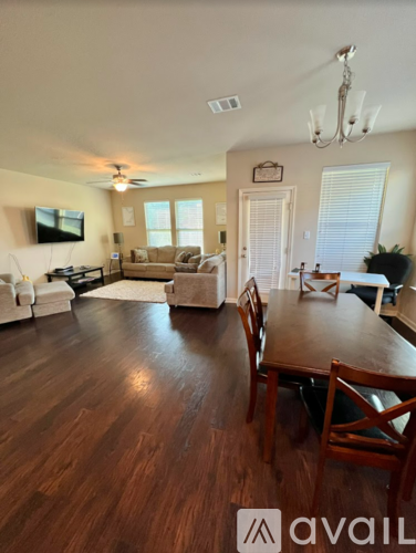 A living room with a wooden floor and a dining table with chairs.