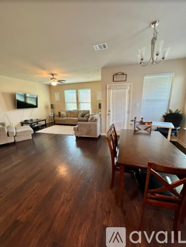 A living room with a wooden floor and a dining table with chairs.