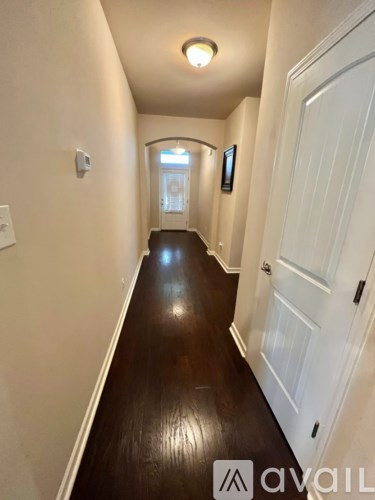 A hallway with a white door and a window in the distance.