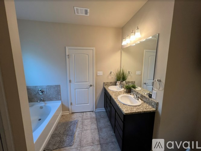 A bathroom with a tub, sink, mirror, and a plant.