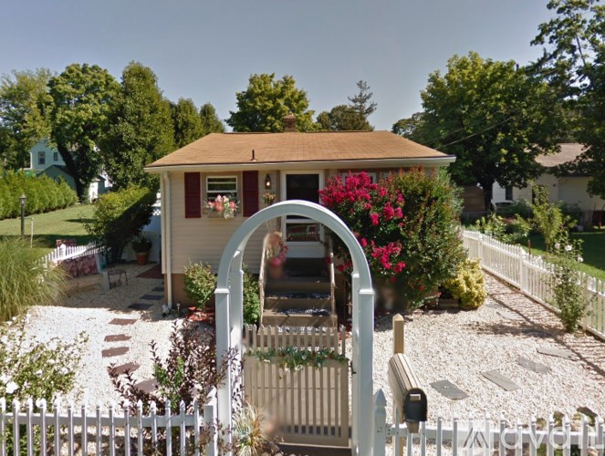 A small house with a white picket fence and a garden in front.