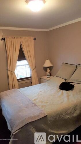 A bedroom with a bed, a lamp, and a window with curtains.