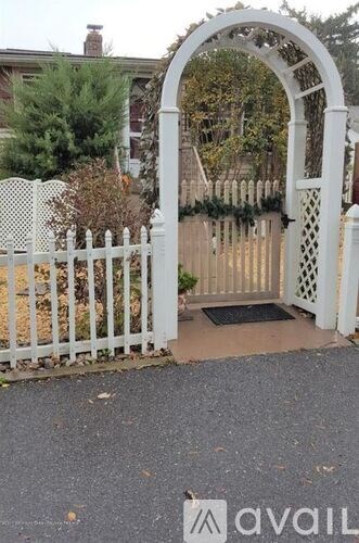 A white gate with a decorative archway leading to a driveway.