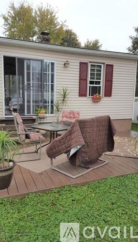 A patio with a table and chairs is in front of a house.