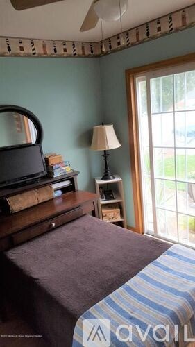 A bedroom with a bed, a dresser, a lamp, and a window.