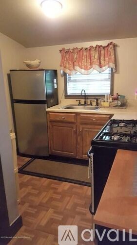 A kitchen with a black fridge and wooden cabinets.