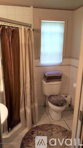 A small bathroom with a toilet, a shower curtain, and a window.