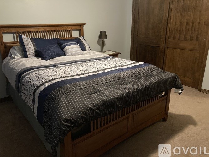 A bed with a wooden headboard and a striped comforter is in the foreground of the image.