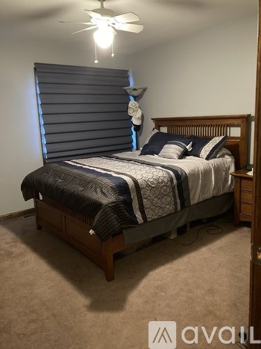 A bedroom with a bed, carpet, and a ceiling fan.