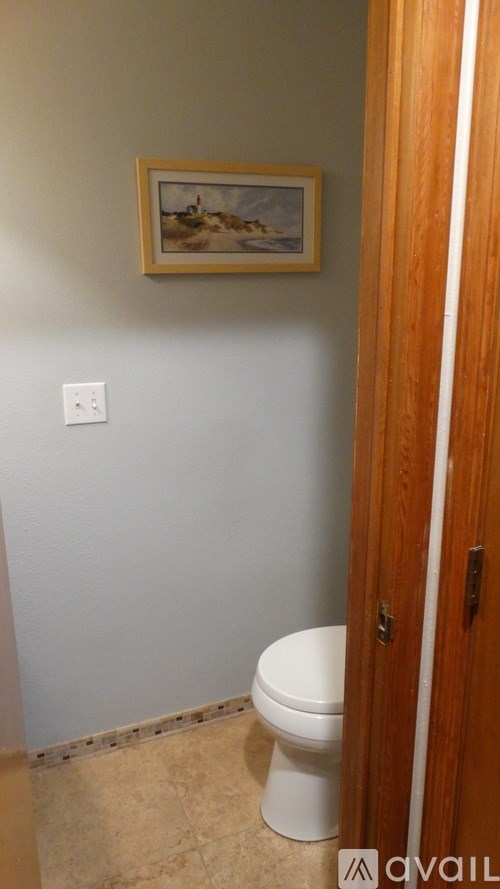 A bathroom with a toilet and a painting on the wall.