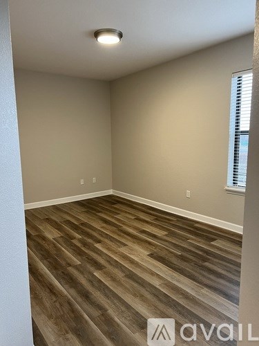 A room with wooden flooring and a window with blinds.