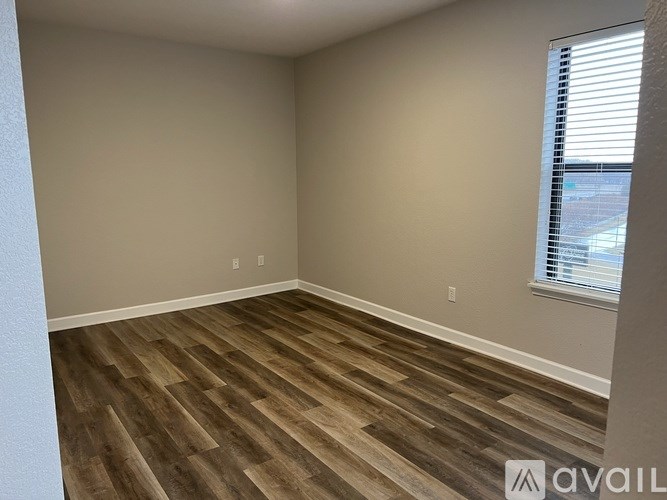 A room with wooden flooring and a window with blinds.
