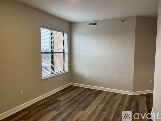 A room with wooden flooring and a window with blinds.