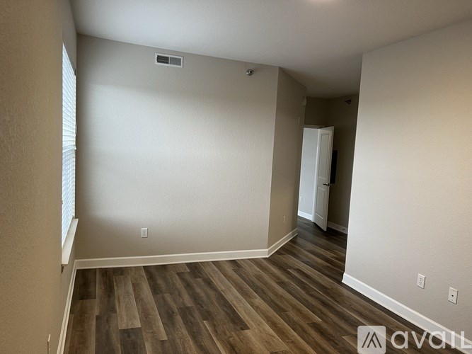 A room with wooden flooring and white walls, with a door on the right side.