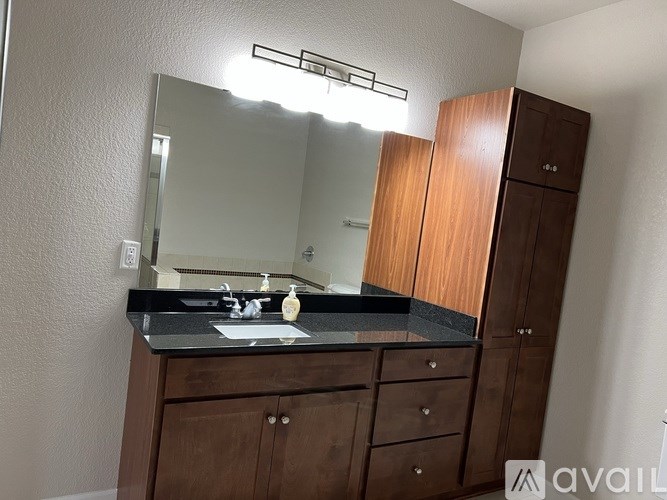 A bathroom with a sink, mirror, and wooden cabinets.