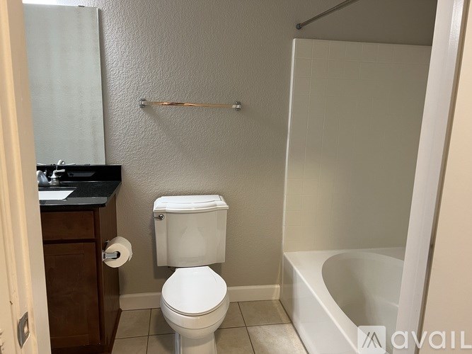A white toilet sits in a small bathroom next to a white bathtub.
