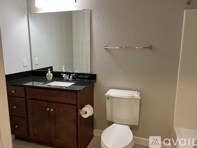 A bathroom with a toilet, sink, and mirror.