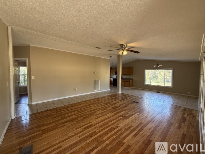 A spacious room with wooden flooring and a ceiling fan.