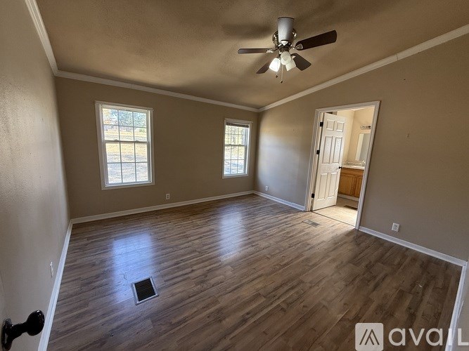 A room with a ceiling fan and wooden flooring.