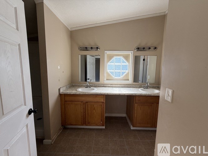 A bathroom with a double sink vanity and a window.