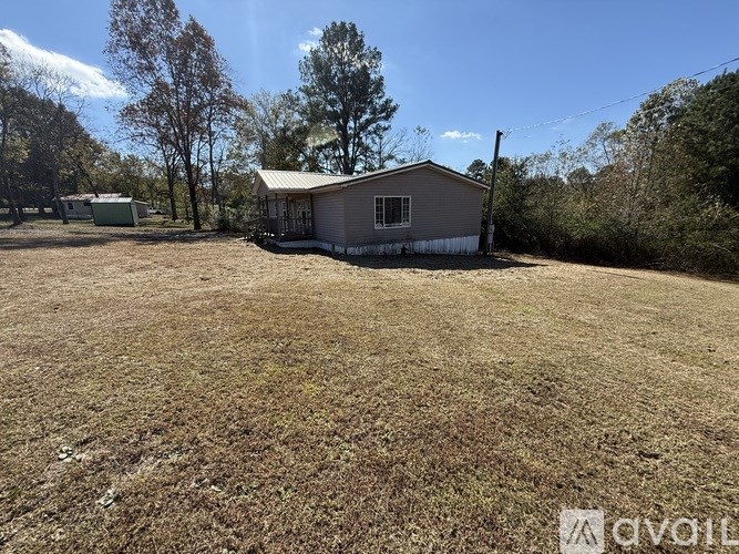 A small house with a metal roof is surrounded by a grassy field.