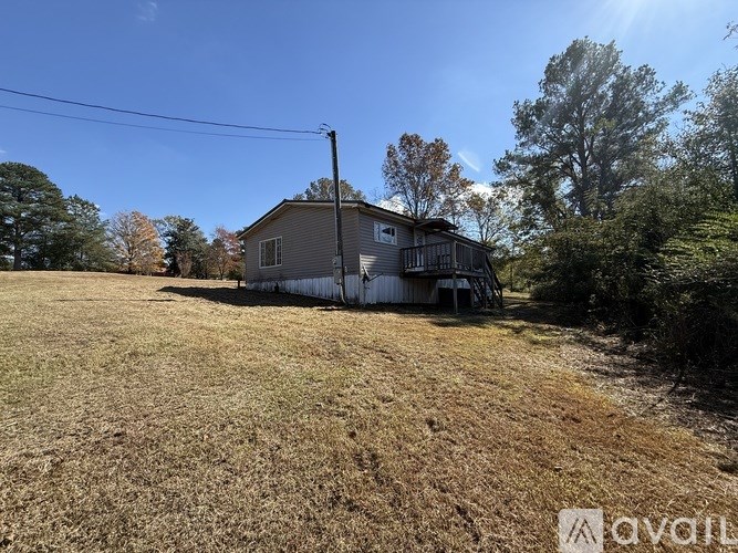 A house with a grey roof and a chimney is surrounded by trees and grass.