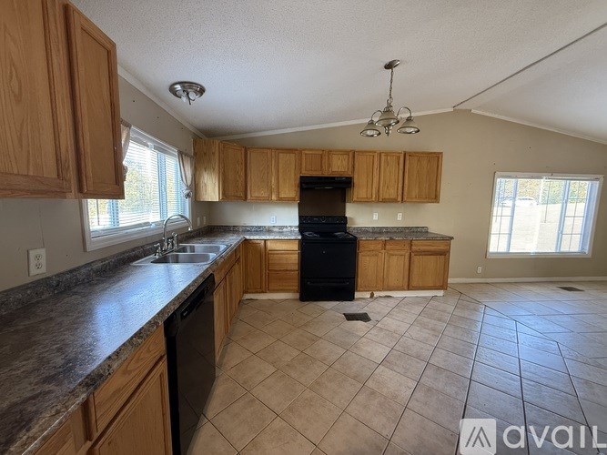A kitchen with wooden cabinets and a black dishwasher.