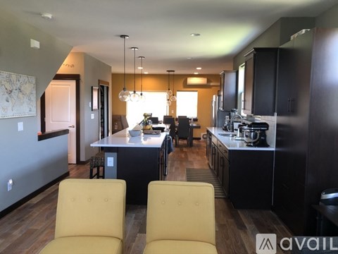 A modern kitchen with black cabinets and a dining area with yellow chairs.
