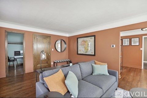 A living room with a grey couch and a map on the wall.