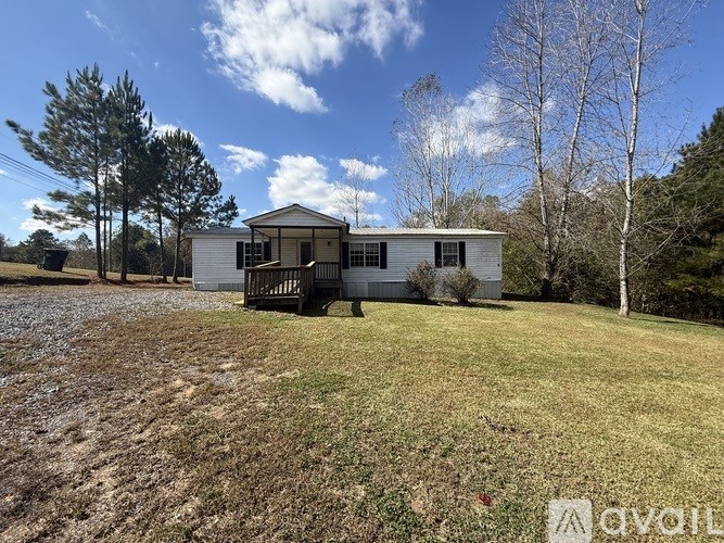 A house with a porch is surrounded by trees and grass.