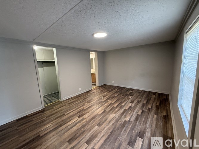 A room with wooden flooring and a window on the right side.