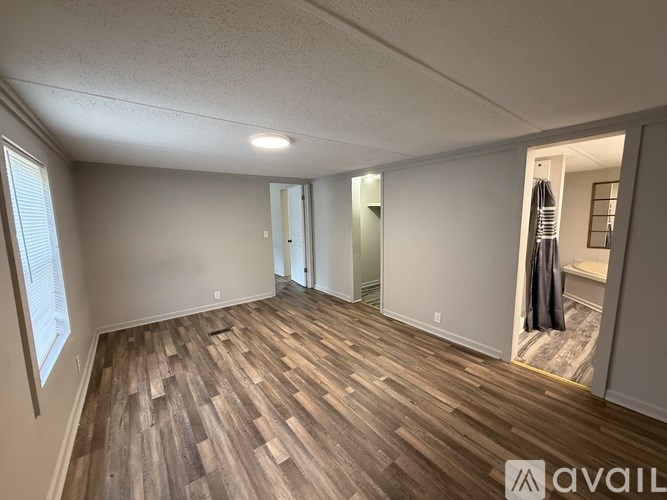 A room with wooden flooring and a window on the left side.