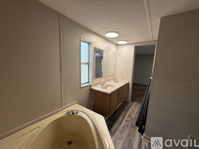 A bathroom with a tub, sink, and mirror.