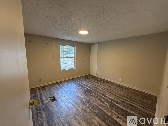 A room with a window and wooden flooring.