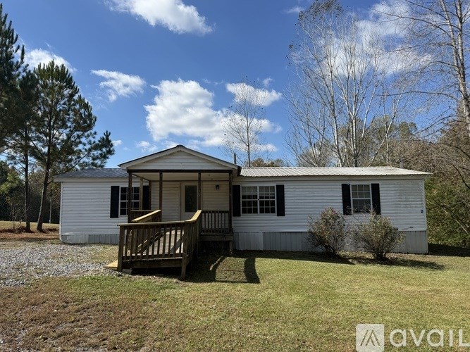 A white house with a porch and a tree in front.