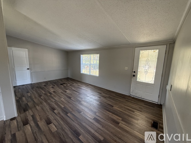 A room with wooden flooring and a window with a white door.