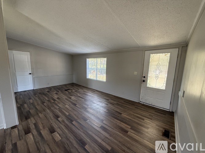 A room with wooden flooring and a window with a white door.
