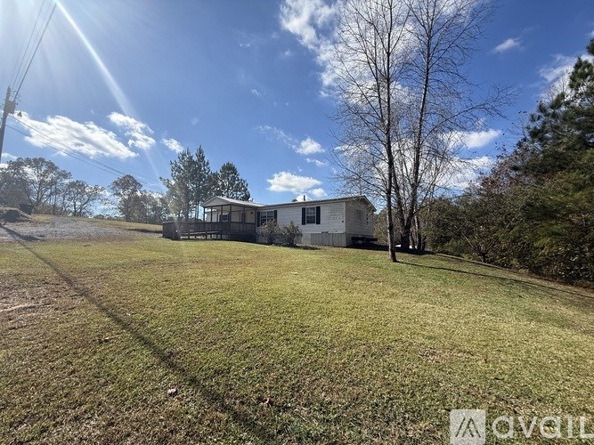 A house is situated in a grassy field with trees around it.