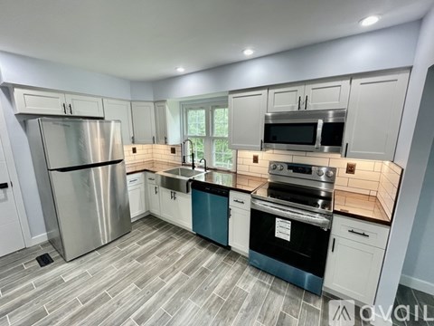 A kitchen with white cabinets and a stainless steel refrigerator.