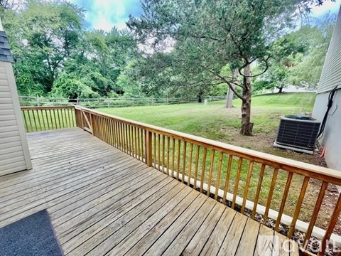 A wooden deck with a railing overlooks a grassy area.