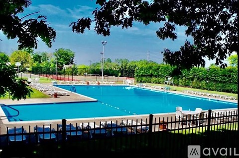 A large outdoor swimming pool surrounded by a fence and trees.