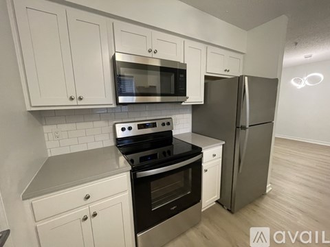 A kitchen with white cabinets and a stainless steel refrigerator.