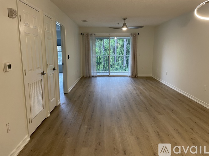 A spacious room with wooden floors and a ceiling fan.
