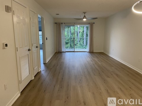 A spacious room with wooden floors and a ceiling fan.