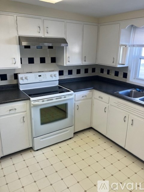 A kitchen with white cabinets and black countertops.