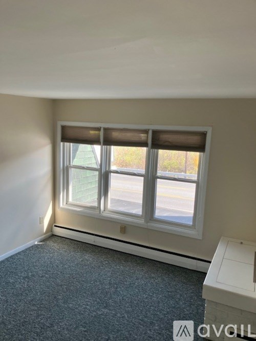 A room with a window and a carpeted floor.