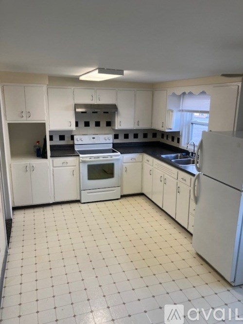 A kitchen with white cabinets and appliances.