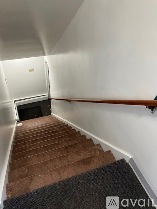 A staircase with a carpeted runner and wooden steps leading to a dark room.