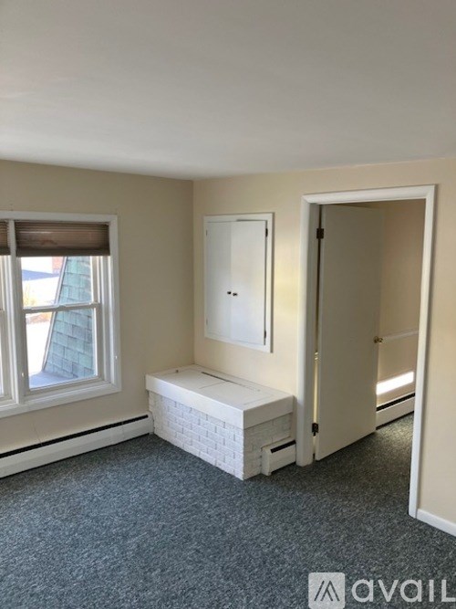 A room with a window, a bench, and a door.